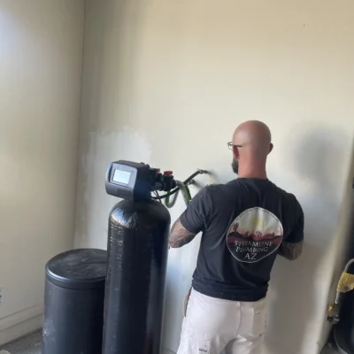 Water softener unit installed in a residential garage, showing clean plumbing connections.