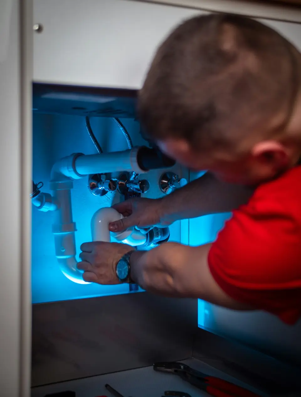 Plumber working on the drain under a bathroom sink